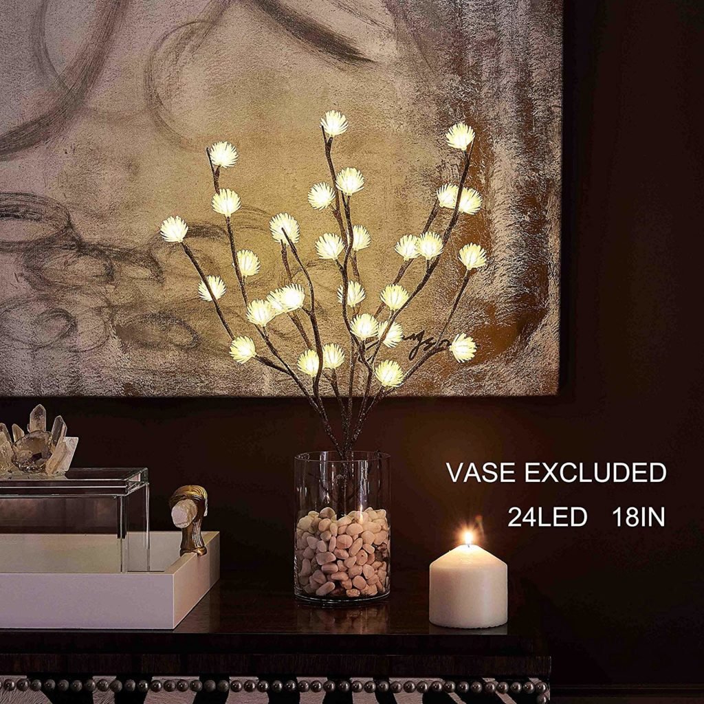 Small LED branch tree in a glass vase beside a candle