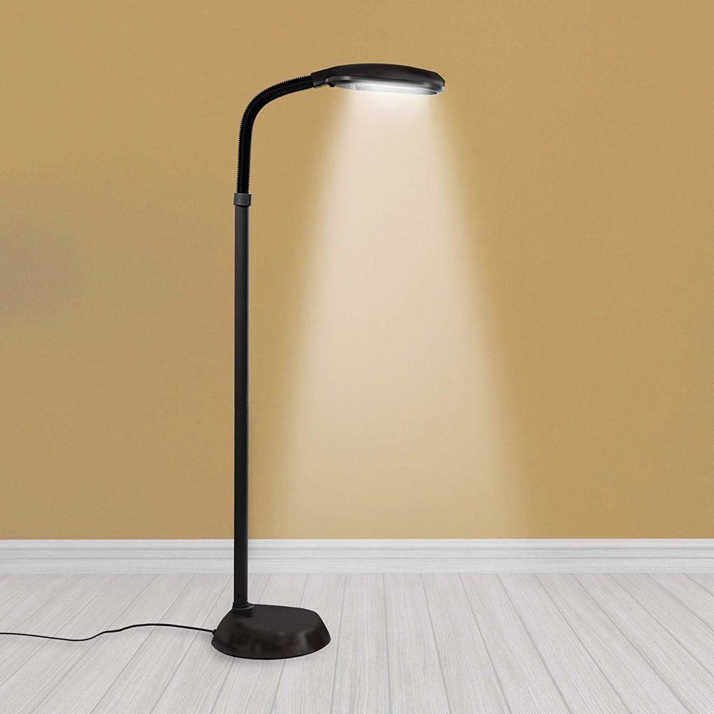 Black floor lamp with a curved neck casting light onto a wall