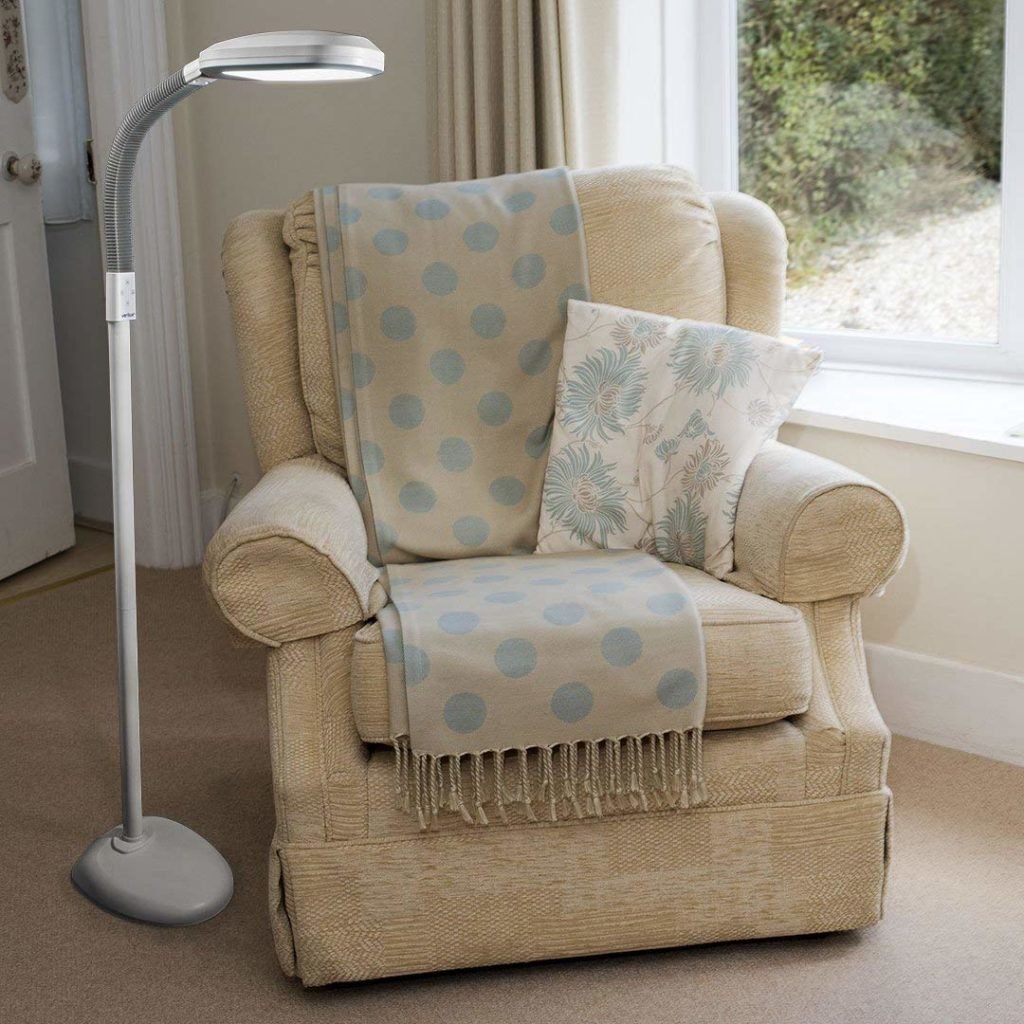 Floor lamp standing beside a beige armchair with a blue patterned throw