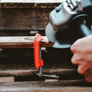 Angle grinder throwing sparks while cutting a clamped metal workpiece