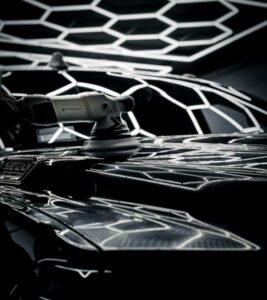 Dual-action machine polisher working on a glossy black car body