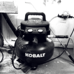 Portable air compressor tank with wheels, gauges and coiled hose