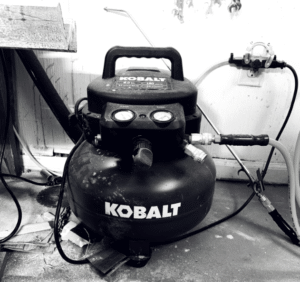 Portable air compressor tank with wheels, gauges and coiled hose