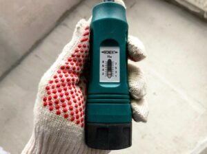 Digital multimeter held in a gloved hand for checking electrical output