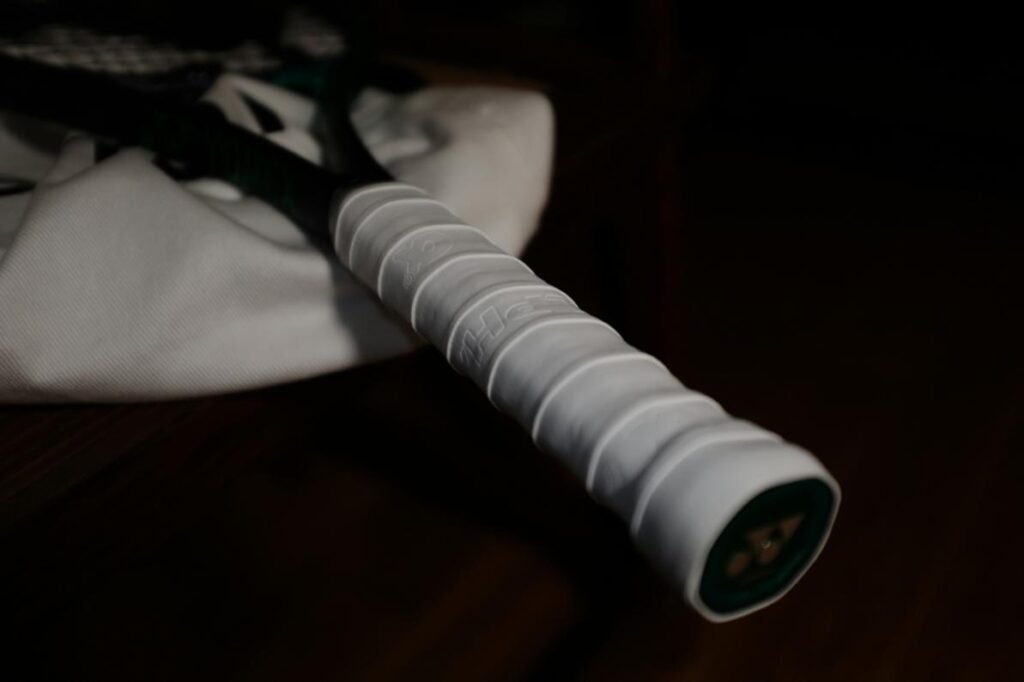 Close-up of a badminton racket handle wrapped in white grip tape